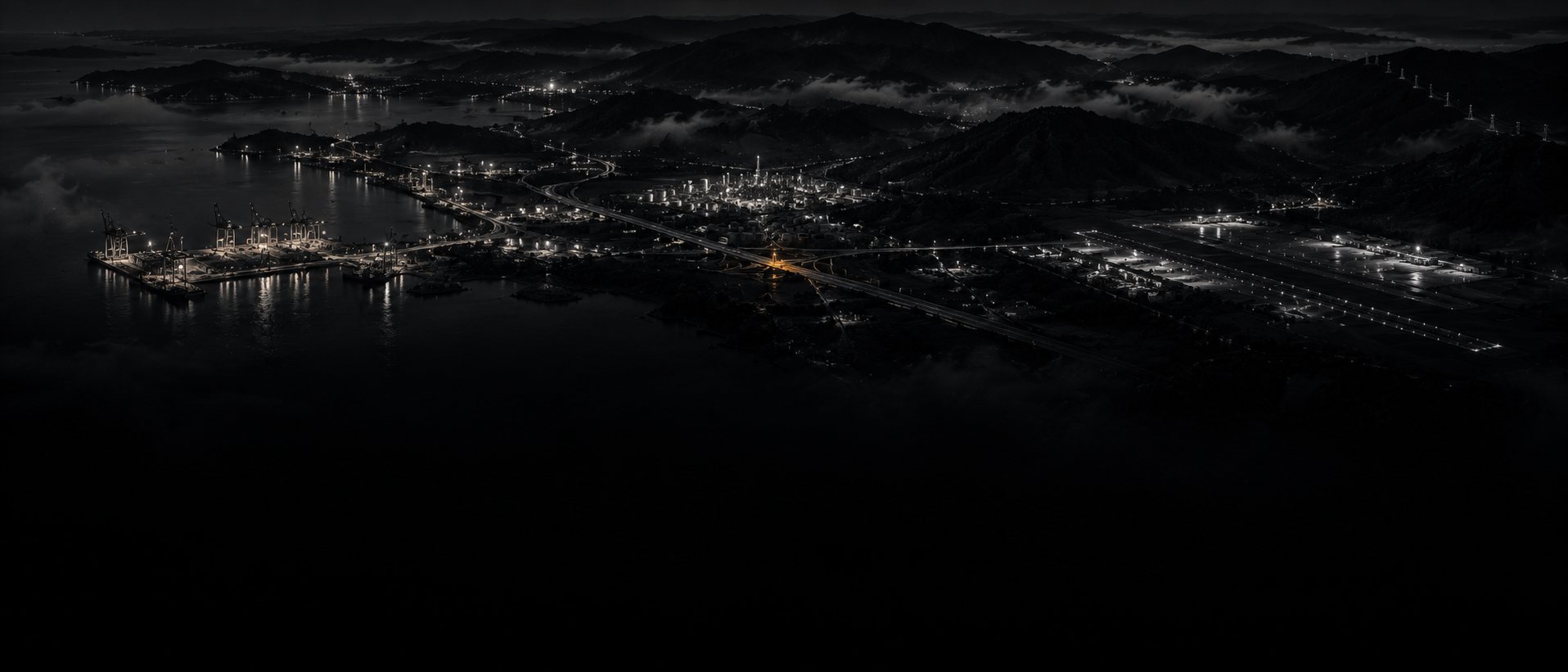 Vista aérea nocturna de una región con puerto, planta industrial, aeropuerto y autopista, como un mapa hecho de luz